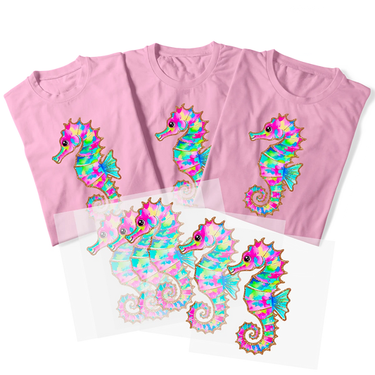 Three pink t-shirts with a custom DTF print of a colorful, psychedelic seahorse, shown with the transfer sheets used to apply the design. This showcases the vibrant colors and sharp detail of DTF printing, perfect for creating personalized beach-themed apparel in Miami.