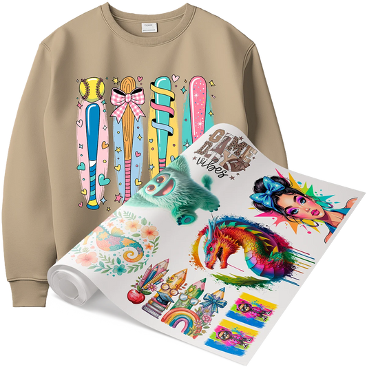 A tan sweatshirt with a custom DTF flexible peel print of a baseball and colorful bats, shown next to a roll of transfers featuring whimsical designs like a dragon, chameleon, and a cute monster. This showcases the soft, flexible feel of DTF prints on custom apparel in Miami.