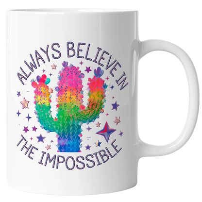 A white coffee mug with a custom DTF print of a colorful rainbow cactus surrounded by stars. The design features the text 'ALWAYS BELIEVE IN THE IMPOSSIBLE,' showcasing high-quality DTF printing for personalized mugs and gifts in Miami.